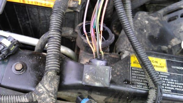 This picture shows bare wires on a connector to a transmission. The harness was pulled from below and laid near the radiator