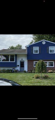 New horizontal blue vinyl siding  and white vertical siding around new front door as a highlight