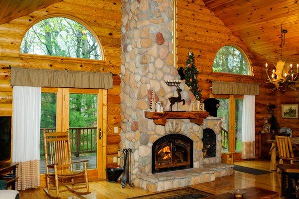 Log cabin with cathedral ceilings and river rock fireplace.