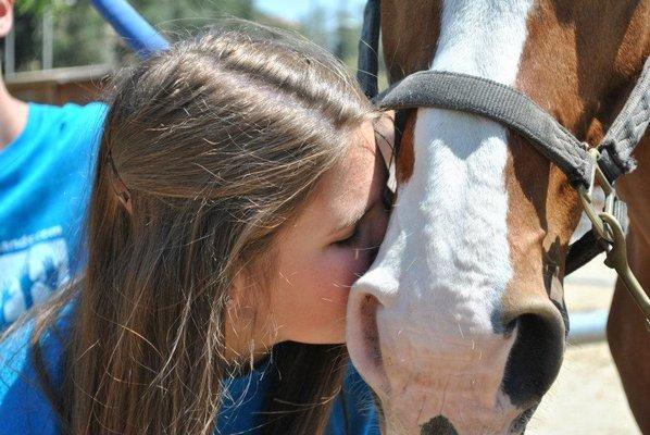 Teen campers helping brush and saddle horses while learning about equine therapy at Rancho St Franics.