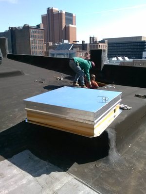 Commercial roofing: installing a hatch on a building in center city.