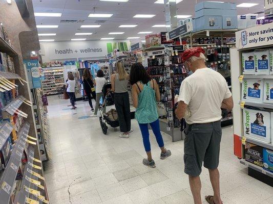 More than 12 people waiting in line at the pharmacy. And the line is longer than that.  There are more people behind me.