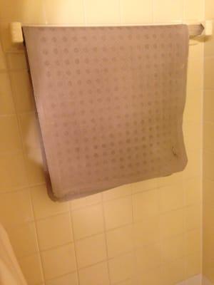 Cracked old bath mat hanging in the shower