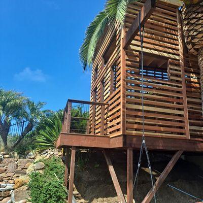 these are pics of a just completed very custom trampoline tree house fort for kids . it features 1x4" clear redwood spaced siding out side