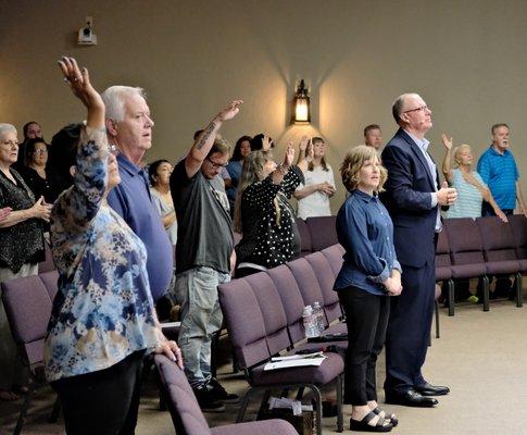 Good News Church family worshipping with Pastor Tom and Sharon at the front