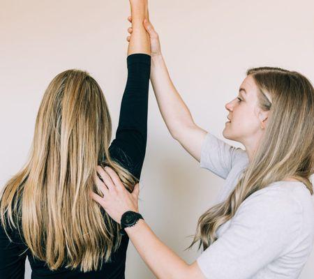 Physical therapist assessing shoulder range of motion improvement.