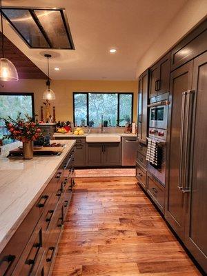 Kitchen showing drawers instead of wall cabinets and colors of cabinets, floor and light from expanded window.