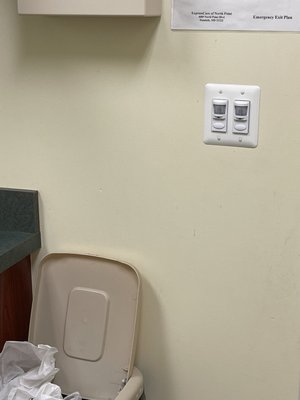 Dried blood on the wall in the exam room, overflowing trash can