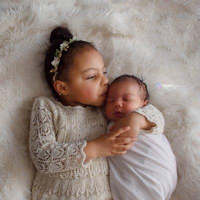 Big sister with newborn little sister in white and cream