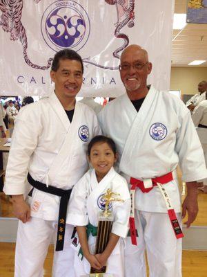 (Left) Sensei Anthony Corpuz, 7th Dan; (Right) Shihan Ferol Arce, 9th Dan congratulating a student on her tournament trophy.