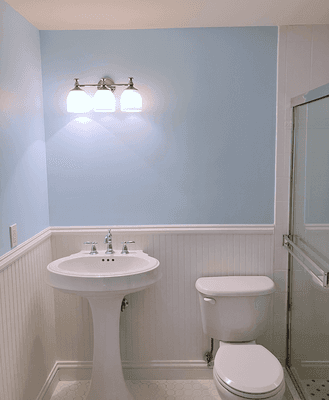 To refresh this sky-blue bathroom, we replaced the fan, upgraded the lights, and repaired/repainted the wainscot.