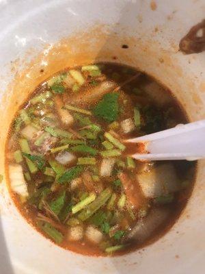 Beef consommé topped with onions and cilantro