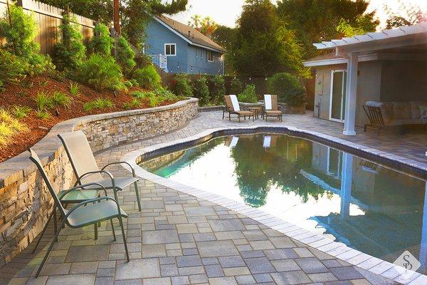 Pool pavers, custom landscape design, paving stone retaining wall and outdoor LED lighting.