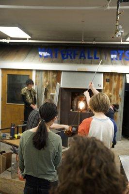 Local middle school student observe a glass blowing demonstration in the Waterfall Arts Glasswork studio