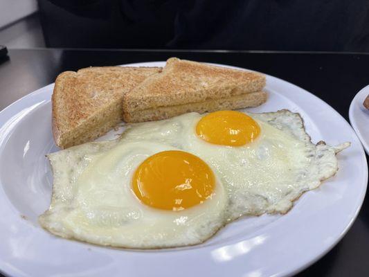 Two sunny side up eggs and whole wheat toast