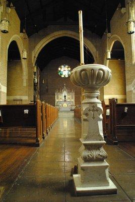 Looking down the aisle from the back of Augustana Lutheran Church, baptismal font shown in the foreground.