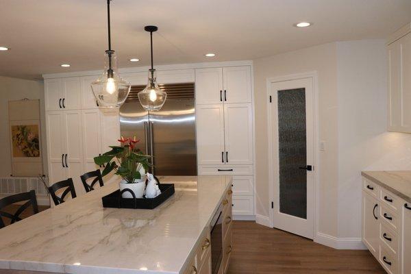 Highlights of this Villa Park kitchen remodel include custom flooring, a kitchen island with bar seating, new appliances & white cabinets.