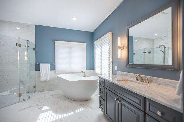 Natural Stone White Carrara Marble countertops. The freestanding tub is Kohlet Abrazo and the shower fixture is Grohe Europhia.