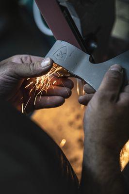 S7 tool steel tomahawk heads getting polished and sharpened.