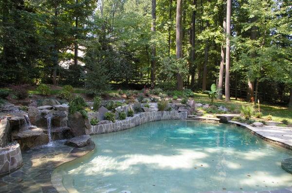 LandArt custom swimming pool installation with natural stone water feature, paver pool deck and landscaping.