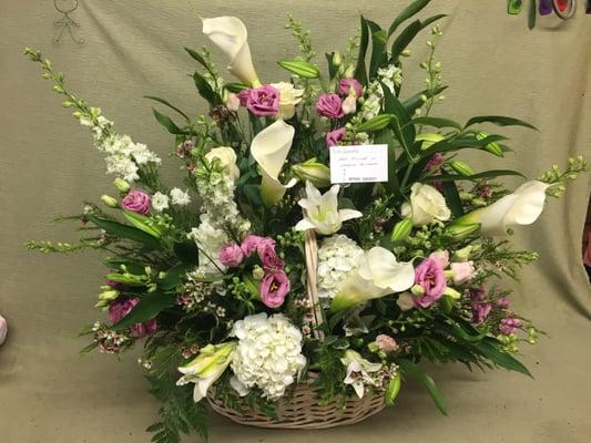 An Elegant Sympathy Basket with calla lilies, lilies, larkspur, hydrangeas, roses, lisianthus, and wax flower.