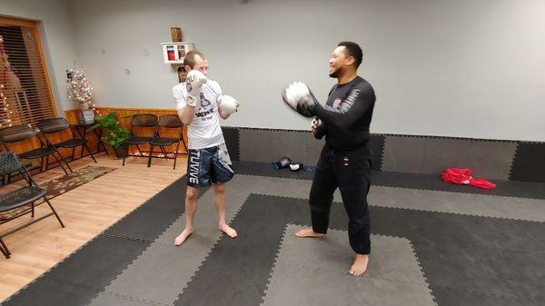 Student and Coach Riser practicing strikes in UJJ's Adult Kickboxing Class.