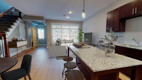 A kitchen with an island leading to a living room with a large window in a loft apartment at Lofts at Saratoga Blvd.