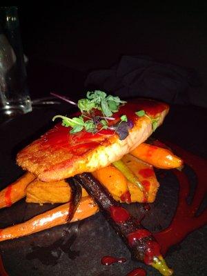 Salmon with orange sauce served over carrots and a chickpea cake