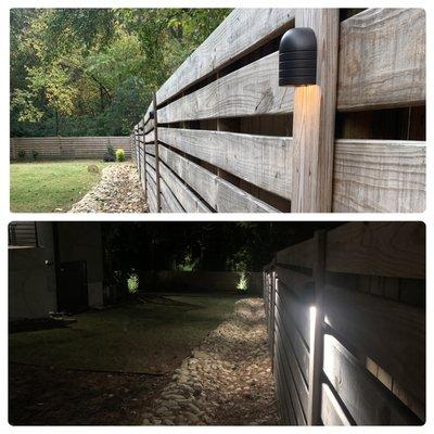 Flush mounted low voltage landscape lighting installed along the fence to accent the river rock below.