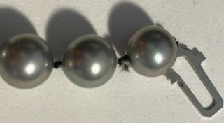 The white material on the black string between the pearls is GLUE.