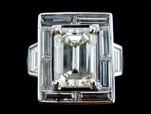 Custom made emerald cut diamond surrounded by long baguettes flanked with trapezoid diamonds crafted in platinum.