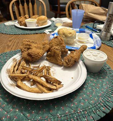 Two chicken dinners.  Some fries were already eaten.  The cole slaw is in the white container.  Look at the BUN!