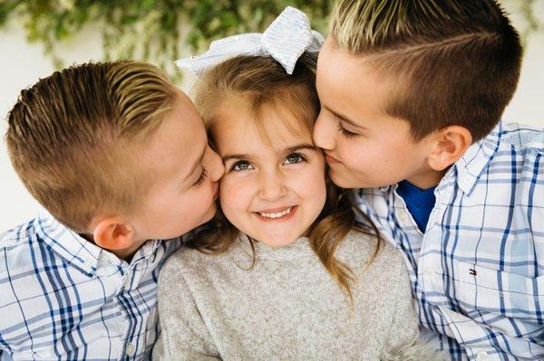 Two boys giving their sister a kiss on the cheek at the Klehm Arboretum and Botanic Garden in Rockford IL