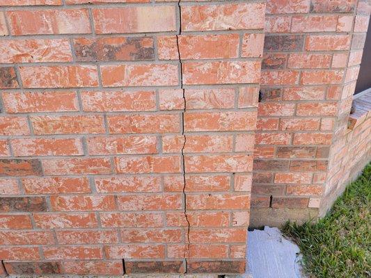 Vertical brick crack resulted from a foundation corner crack.  Foundation corner cracked and broke away from the slab.   No support - CRACK!