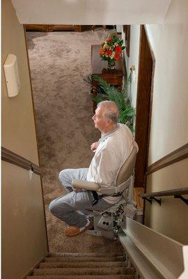 senior riding curved stair lift in his home in Elk Grove, IL