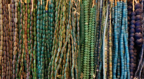 Close up of some strands of African trade beads, strung on raffia in African for sale abroad.  Many have names..watermelon, aja, vaseline...