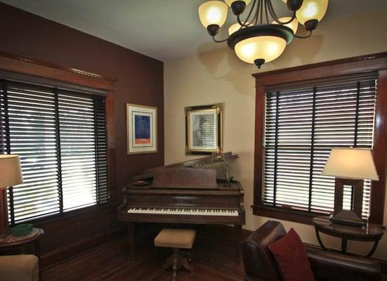 Formal parlor with grand piano, fireplace and TV.