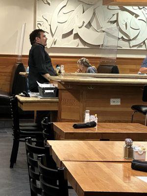 Bartender eating chips behind the bar and serving people drinks.