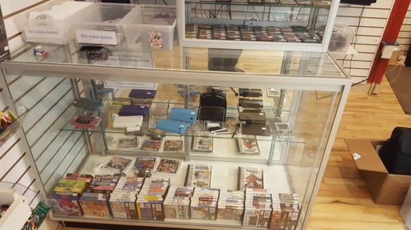 Glass case with portable consoles and games.