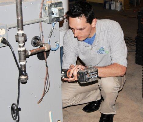 Aric, one of our IAQ technicians, removes a panel to clean the blower of the furnace.