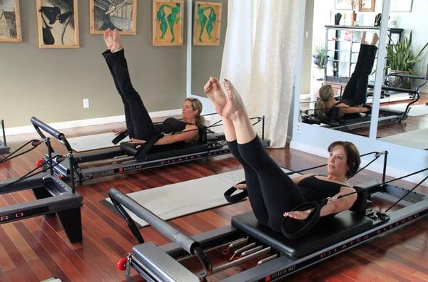 Megan (owner) and Lydia teaching on the reformer machines