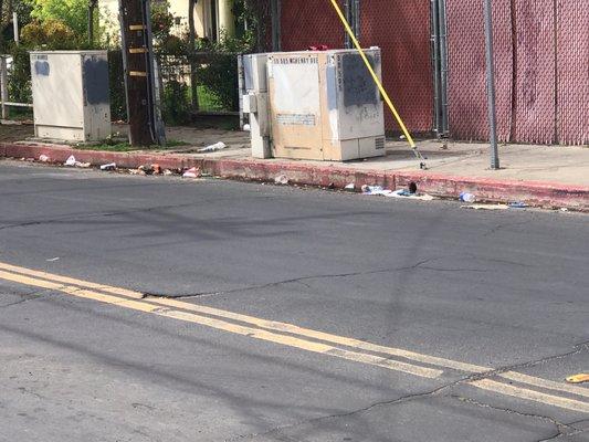 Garbage dumped in the gutter and sidewalk by 7/Eleven customers on the side of their store.