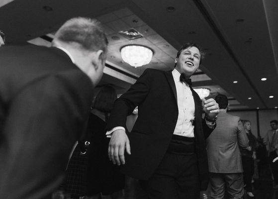 Black and white image of groom dancing and partying at wedding reception