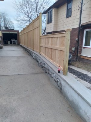 New cedar fence, restored boulder wall, and Bluestone patio by Bianco's Landscaping & Masonry.