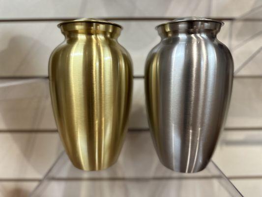 A brass and silver cremation urns for ashes