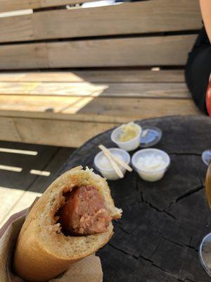 Smoked brat in their easy-to-eat roll/bread thing with onions and sauerkraut in the background