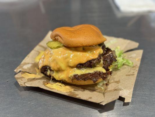 Double cheeseburger with pickles, sauce, caramelized onions, and additional lettuce