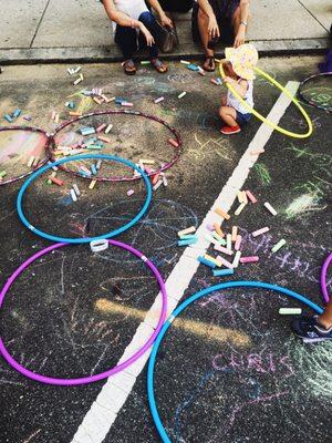 Hula hoops and chalk provided under shady tent.