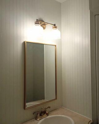 Newly installed light fixture, mirror and beadboard wall.