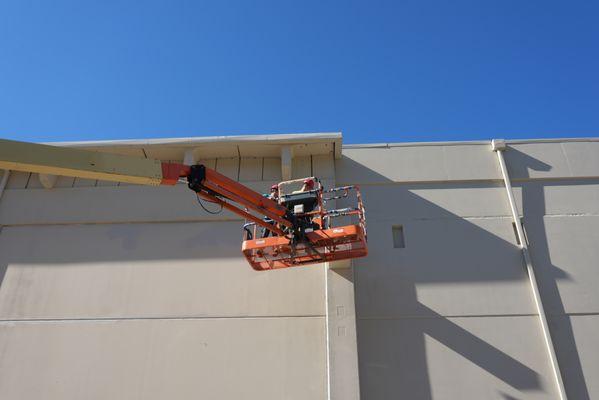 Using lift to spray high areas at a commercial site